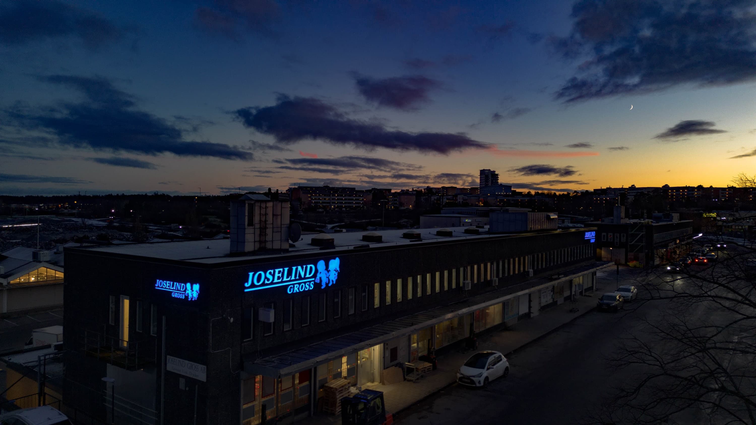 Belyst fasadskylt för Joselind Gross i skymningen
