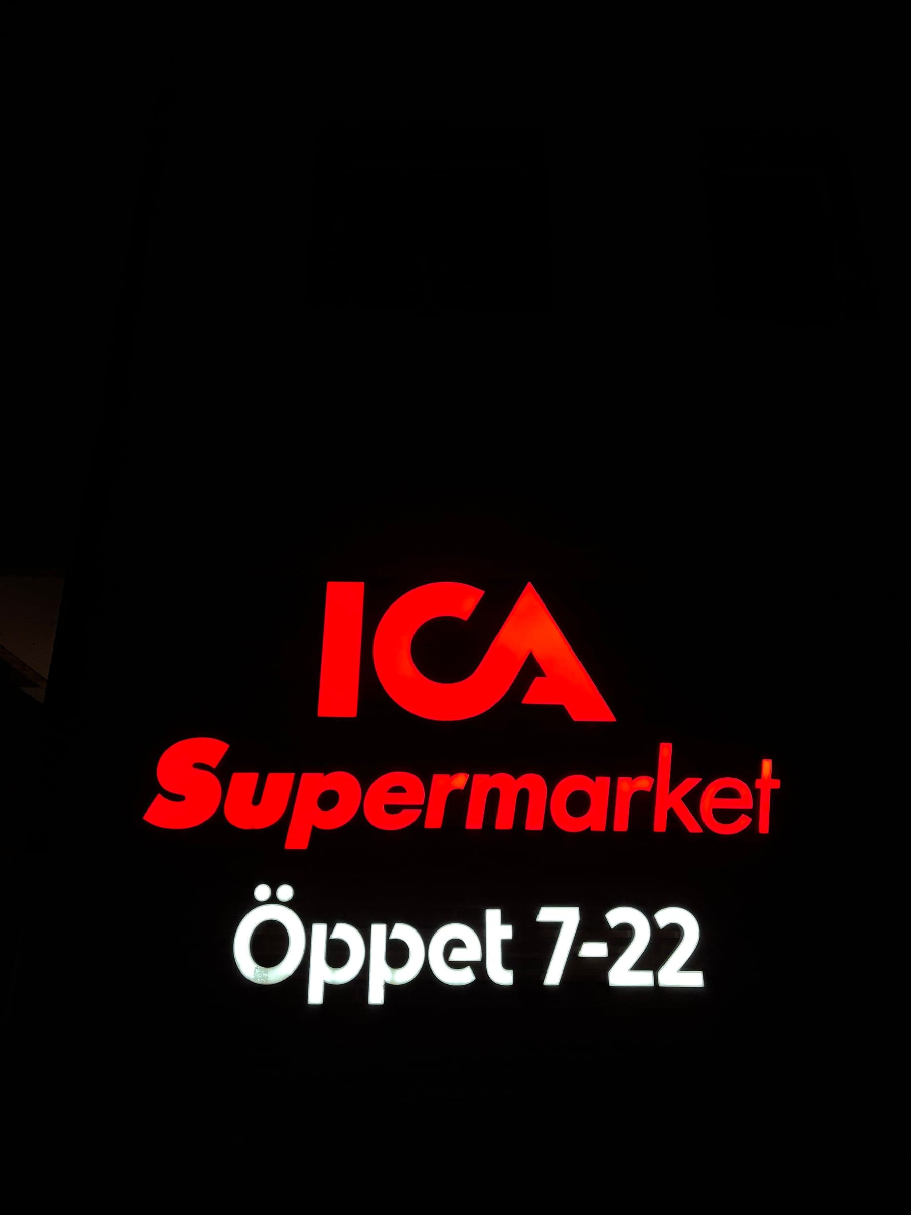 Fasadskylt för ICA Supermarket i Stockholm – röda 3D LED-bokstäver och belyst öppettidsskylt på kvällen