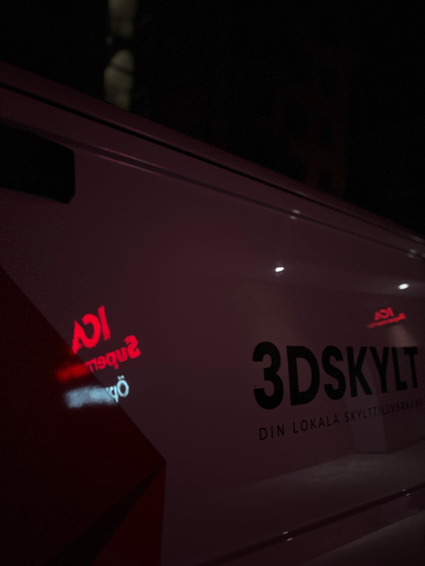 3D Skylts servicebil vid montaget av ICA Supermarkets skylt i Stockholm – skylten speglas i bilen