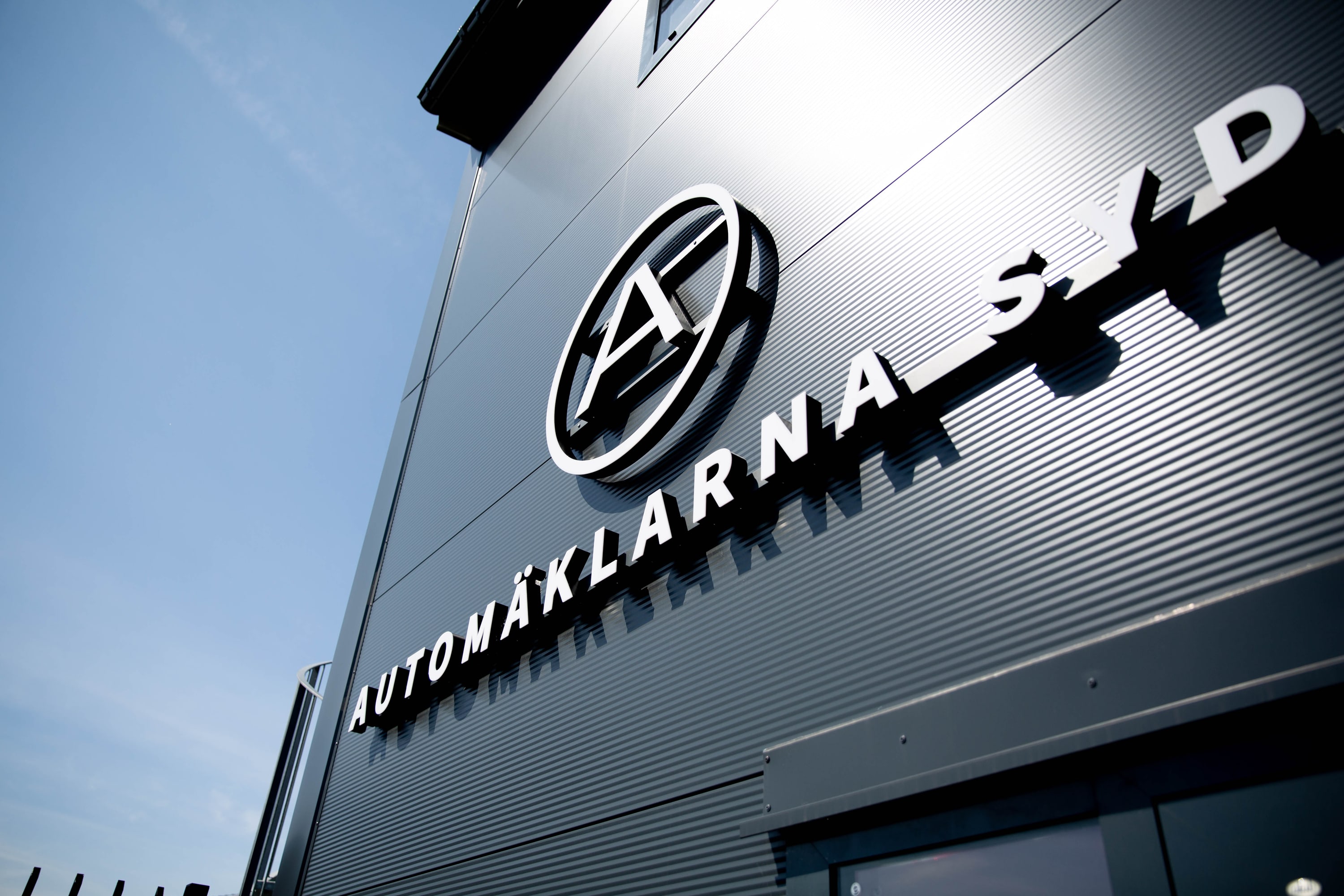 3D-bokstäver för Automäklarna Syd på en mörk plåtfasad i dagsljus