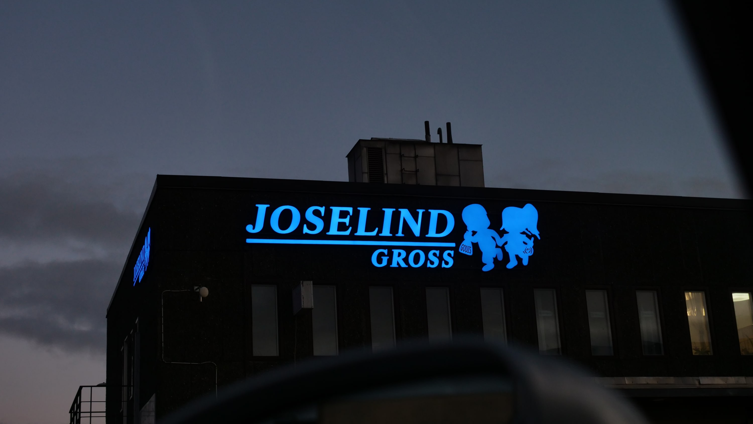 Joselind Gross blå LED-skylt på mörk fasad